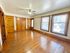Bright, spacious room with gleaming hardwood floors, wooden panel doors, and large windows offering ample natural light.