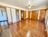 Bright and spacious room with polished hardwood floors, classic wooden doors, and a ceiling fan, boasting elegant mid-century charm.