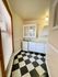 Bright, cozy kitchen corner featuring vintage checkerboard flooring, a compact stove, and classic white cabinetry with natural light pouring in.