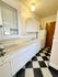 Charming galley kitchen with sleek white cabinets, checkered black and white flooring, and modern lighting.