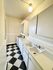 Charming kitchen with vintage checkered floor, ample white cabinetry, and dual sink setup under soft lighting.