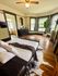 Charming bedroom with large bay windows, cozy decor, and modern accents, featuring a plush bed and vibrant indoor plant.