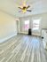 Bright room featuring elegant wood flooring, modern ceiling fan, and expansive windows for natural light.