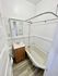 Charming bathroom with vintage clawfoot tub, compact vanity, and minimalist white decor.