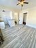 Bright and inviting room with modern laminate flooring, sleek ceiling fan, and a compact kitchen corner leading to a cozy bathroom. Ideal for comfortable urban living.