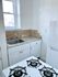 Charming kitchen with natural light, featuring a sleek countertop, elegant white cabinetry, and a classic gas stove.