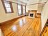 Charming living room with hardwood floors, large windows, and a cozy fireplace, offering natural light and elegant wood finishes.