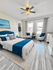 Elegant bedroom with a modern blue theme, featuring a cozy double bed, plush seating area, and abundant natural light from large windows.