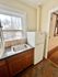 Cozy kitchen corner featuring a large window, sleek countertop, and compact refrigerator, offering cityscape views.