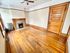 Charming apartment room with wooden floors, a classic fireplace, and vintage wooden door, exuding warmth and character.