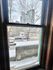 Charming city view from a cozy apartment window, showcasing modern high-rise buildings and a snowy urban street.