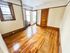 Charming room with polished hardwood floors, natural light from large windows, and classic wood trim accents.