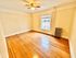 Bright and spacious room with gleaming hardwood floors, ceiling fan, and large window offering natural light, perfect for an inviting atmosphere.