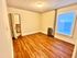 Bright and inviting room with warm wood flooring, soft lighting, and ample natural light from a large window.