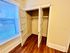 Charming closet space with double doors and warm wood flooring, enhanced by natural light from a nearby window.