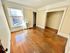 Charming sunlit room with large window, hardwood floors, and spacious open closet, perfect for cozy living.