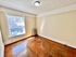 Bright and airy room with large window, showcasing polished wooden floors and a classic radiator, offering a touch of vintage charm.
