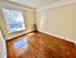 Bright, spacious room with hardwood floors and large window offering natural light.