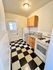 Charming narrow kitchen with classic black and white checkered floor, warm wooden cabinets, and bright natural light.