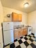 Charming kitchen with classic black and white checkered floor, featuring wooden cabinets, a gas stove, and a double sink for optimal cooking convenience.