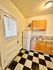 Charming kitchen with classic black and white checkered flooring, warm wooden cabinets, and modern lighting.