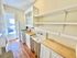 Charming galley kitchen with natural wood countertops, open shelving, and ample natural light from large window.