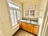 Bright kitchen with vintage charm, featuring large windows, wooden cabinetry, and a classic checkered backsplash.