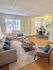 Inviting living room with modern decor, featuring a cozy sofa, sleek coffee table, and a stylish dining area with a glass table, ideal for relaxing and entertaining.