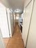 Inviting hallway leading to a cozy kitchen with modern appliances and warm wooden flooring, ideal for compact living spaces.