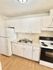 Bright and functional kitchen with modern white cabinetry, double sink, and sleek black appliances, offering a contemporary cooking space.
