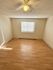 Bright, spacious room with wood flooring and a ceiling fan, perfect for creating a cozy and inviting space.