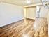 Charming apartment with beautiful hardwood flooring, spacious living area, and a peek into a modern kitchen.