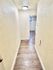 Bright corridor with elegant wooden flooring, leading to a well-lit room in a stylish apartment.