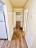 Bright hallway in apartment with elegant wood flooring and modern white walls, leading to multiple rooms.