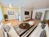 Inviting living area with stylish decor, featuring a cozy cream sofa, wooden coffee table, and decorative plants, complemented by a wall-mounted TV and bookshelf.