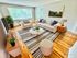 Chic living room with a modern design, featuring stylish white furniture, a striped rug, and large windows with abundant natural light.
