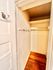 Inviting walk-in closet with ample shelving and hooks on warm wooden flooring, perfect for organized storage.