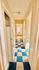 Charming hallway with blue and beige checkered flooring leading to a bright, sunlit room.