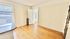 Bright and spacious room with hardwood floors, large window, and classic white walls, ideal for a cozy living area or bedroom.