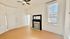 Charming room with a classic fireplace, large window, and ceiling fan, offering abundant natural light and elegant simplicity.