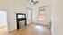 Bright living room with classic fireplace, ceiling fan, and large windows letting in natural light.