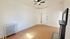 Bright room with elegant hardwood flooring, vintage radiator, ceiling fan, and classic fireplace, ideal for cozy living space.