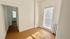Bright and airy room with plentiful natural light, featuring warm-toned flooring and white walls, perfect for a cozy setup.