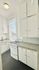 Bright, charming kitchen featuring vintage white cabinetry, a cozy stove, and a large window with natural light.
