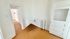 Bright and inviting entrance with a classic white door, featuring warm wood flooring and stylish radiator heating.