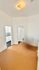 Inviting room entrance with warm lighting and doors leading to a quaint kitchen featuring classic white cabinetry.