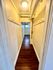 Inviting hallway with elegant wood flooring, stylish lighting, and ample storage hooks, leading to a bright, spacious room.