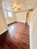 Charming room with sleek wooden flooring, built-in shelving, and ample natural light from large windows, perfect for a cozy living space.