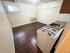 Charming kitchen with wooden flooring, brick accent wall, and vintage gas stove, offering cozy and rustic appeal.