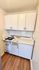 Compact kitchen with retro white cabinetry and gas stove, ideal for urban living.
